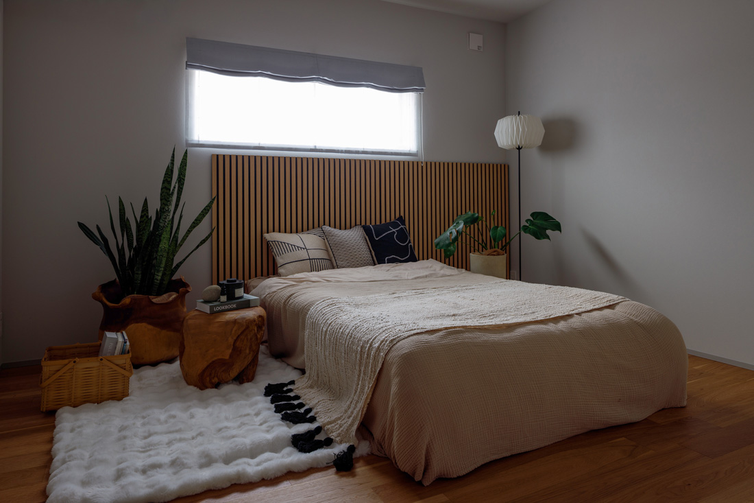横長の窓を設けた落ち着きのあるシンプルな寝室