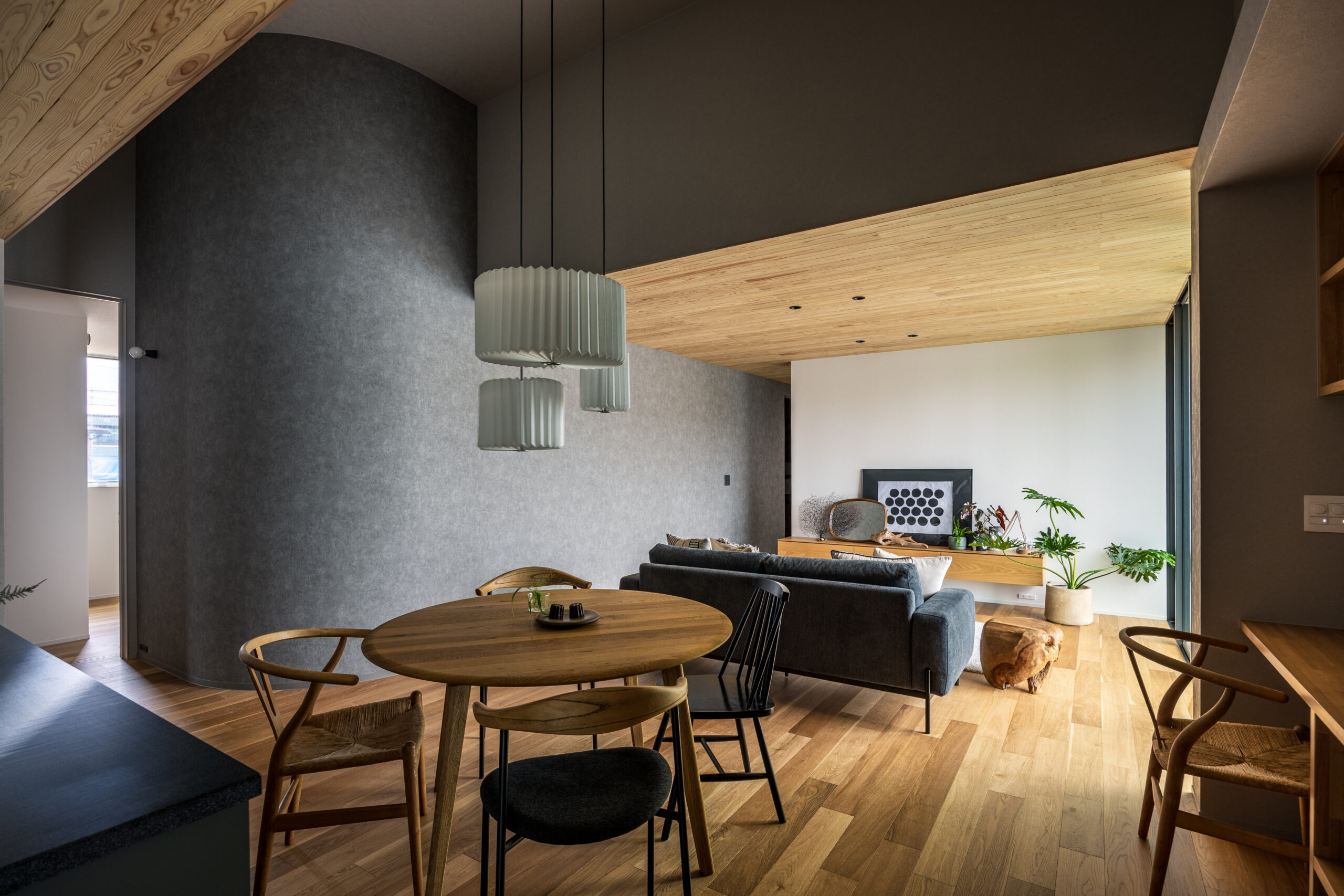 高松市六条町の平屋モデルハウス。木目天井とグレーのアール壁が調和する、ダイニングからリビングを望むLDK。
