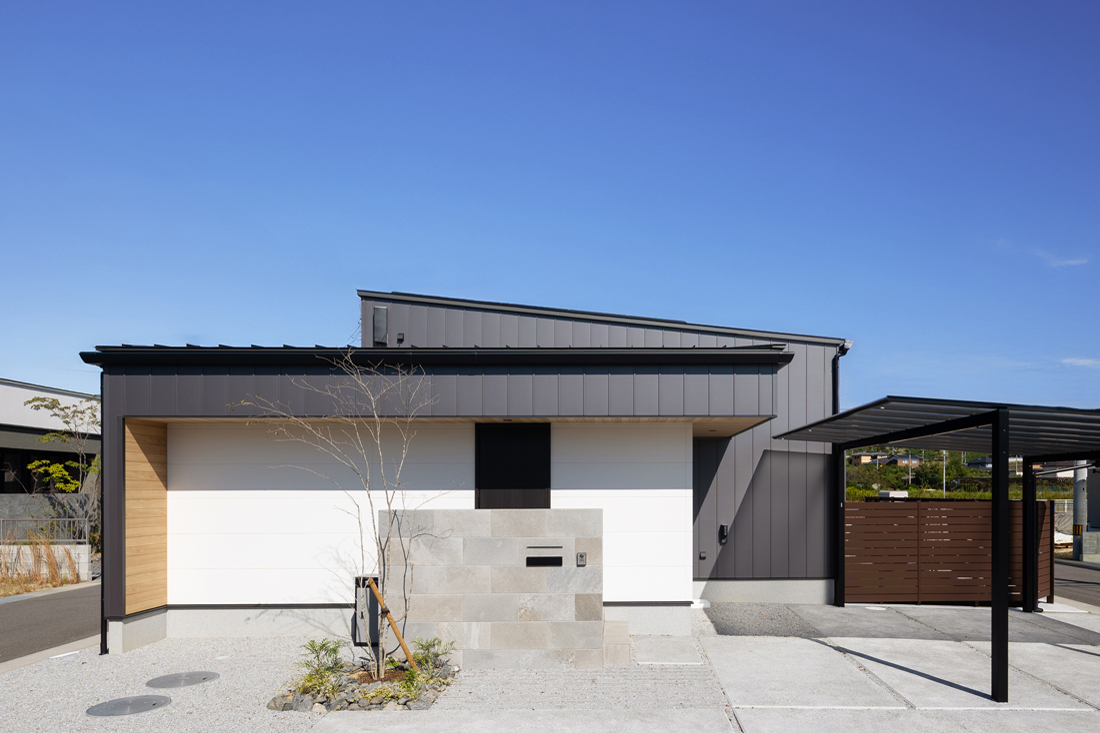 黒のガルバリウムと白のサイディングに木目をポイントとした平屋