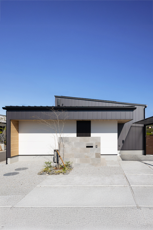 黒のガルバリウムと白のサイディングに木目をポイントとした平屋