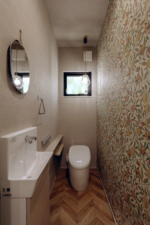 ボタニカル柄のクロスとヘリンボーン柄の床のトイレ